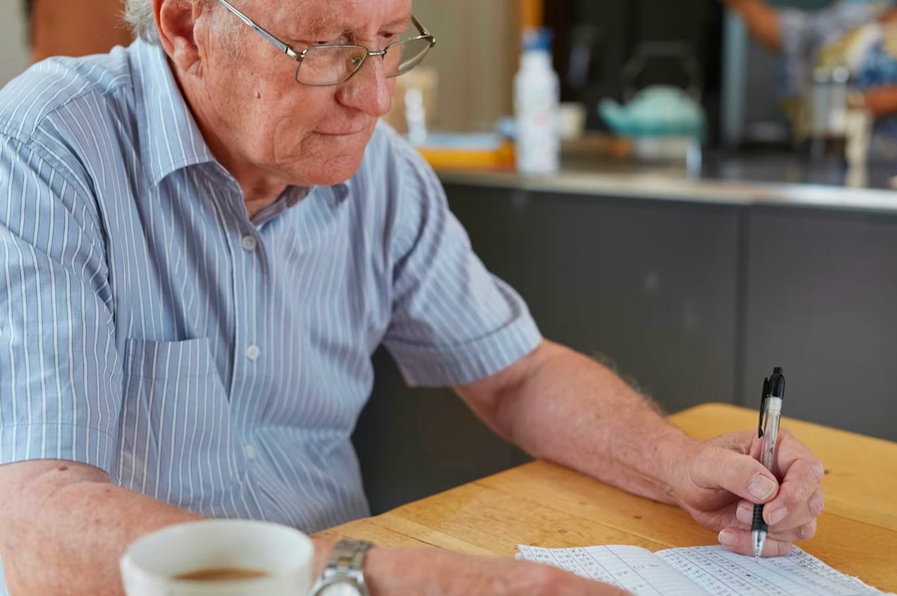 Old man sat at a table writing