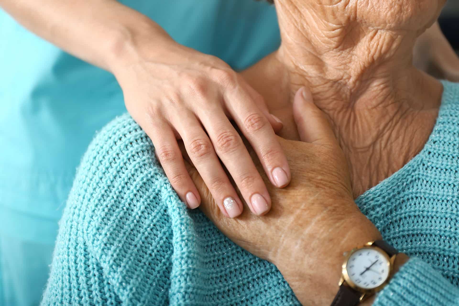 Young persons hand over old persons hand on old persons shoulder